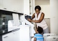 African descent kid helping mom doing the laundry