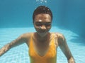 African descent woman smiling underwater in swimming pool