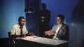 African detective questioning suspect caucasian man in interrogation room. Royalty Free Stock Photo