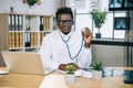 African doctor sitting at office and holding stethoscope