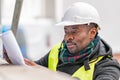 African engineer checking office blueprints on construction site Royalty Free Stock Photo