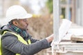 African engineer checking office blueprints on construction site Royalty Free Stock Photo