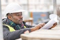 African engineer checking office blueprints on construction site Royalty Free Stock Photo