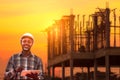 African Engineer man use tablet device standing communication at construction building background on sunset.Concept of engineering Royalty Free Stock Photo