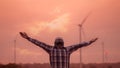 African engineer windmills wearing white hard hat standing with wind turbine on silhouette sunset