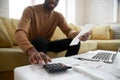 African ethnicity man calculates digits using calculator planning family budget Royalty Free Stock Photo