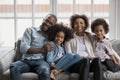 African ethnicity couple and little children photoshooting seated on sofa