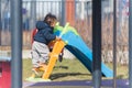 An african ethnicity 5 years old boy dreassed in winter clothing is making his way for a slide in a children's Royalty Free Stock Photo