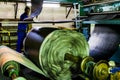 African factory worker checking a roll of rubber on a machine in a conveyor belt factory