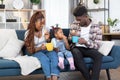 African family of three enjoying snack break on comfy couch