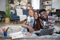 African family using laptop and drawing on floor Royalty Free Stock Photo