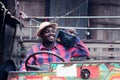 African farmer man with retro radio broadcast receiver on shoulder stands happy smiling outdoor on old tractor background