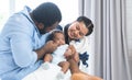 African father and Asian beautiful mother holding cute newborn baby in arms, playing and looking at infant with love and care at Royalty Free Stock Photo