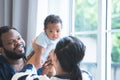 African father and Asian mother carrying cute newborn baby up in the air, playing and looking at infant with love and care at home Royalty Free Stock Photo