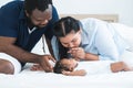 African father and Asian mother kissing hand of cute newborn baby sleeping lying on bed, smiling looking at innocent infant with Royalty Free Stock Photo