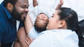 African father and Asian mother lying with cute newborn baby sleeping on bed at home, parents smiling looking at infant with love Royalty Free Stock Photo