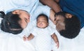 African father and Asian mother lying with cute newborn baby sleeping on bed at home, parents smiling looking at infant with love Royalty Free Stock Photo