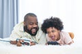 African father and child son playing online video games, using joysticks or game console, having fun at home while lying on bed Royalty Free Stock Photo
