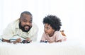 African father and child son playing online video games, using joysticks or game console, having fun at home, lying on bed and Royalty Free Stock Photo