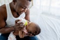 African father Sitting on bed, and feed milk from bottle milk to his 3-month-old baby newborn Royalty Free Stock Photo