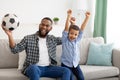 African Father And Son Watching Soccer Game On TV Indoor Royalty Free Stock Photo