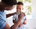 African father, teaching son and toothbrush with care, love or support for cleaning, hygiene or dental wellness. Black