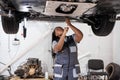 African female auto mechanic fixing car, mechanic repairing car on lift in garage Royalty Free Stock Photo