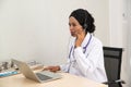 African female Doctor typing on laptop computer while sitting at the desk in hospital office. Physician at work. Royalty Free Stock Photo