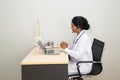 African female Doctor looking on laptop computer while sitting at the desk in hospital office. Royalty Free Stock Photo