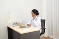 African female Doctor typing on laptop computer while sitting at the desk in hospital office. Physician at work. Royalty Free Stock Photo