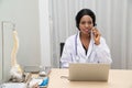 African female Doctor typing on laptop computer while sitting at the desk in hospital office. Physician at work. Royalty Free Stock Photo