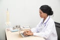 African female Doctor typing on laptop computer while sitting at the desk in hospital office. Physician at work. Royalty Free Stock Photo