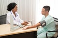 African female Doctor measuring Caucasian male patient blood with pressure Measuring. Royalty Free Stock Photo