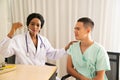 African female doctor, measuring body heat male patient by using a thermometer.