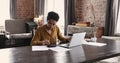 African female sit at desk with laptop do accountancy job