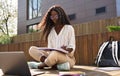 African female student writing notes elearning using laptop studying outside. Royalty Free Stock Photo