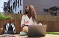 African female student writing notes elearning using laptop studying outside. Royalty Free Stock Photo