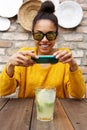 African female taking picture of a drink at cafe