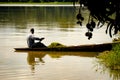 African fisherman man rows his small wooden boat across a lake and collects aquatic plants, Accra, Ghana, Africa