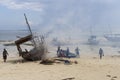 African fishermen set fire under their traditional wooden Dhow boat on the beach to protect it from pests and woodworm and repair Royalty Free Stock Photo