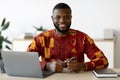 African Freelancer Guy In Traditional Costume Sitting At Desk At Home Office Royalty Free Stock Photo