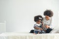 African full family sit on bed in living room play with little kids parents tickles children daughter happy time Royalty Free Stock Photo