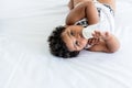 African girl age 2 year and 6 months, lying on a white bed and sucking milk from plastic bottles Royalty Free Stock Photo