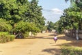 African girl with big backpack running on sandy road to primary school, Mozambique