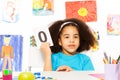 African girl holds flashcard with zero at desk