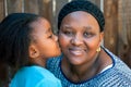African girl kissing mother on cheek. Royalty Free Stock Photo