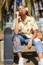 African girl with skateboard relaxing after riding skateboard listening to the music