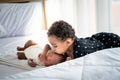 African girl who is an older sister, one year and 6 months old, is kissing brother Royalty Free Stock Photo