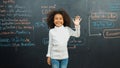 African girl writing and turn around to waving at camera at board. Erudition. Royalty Free Stock Photo