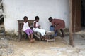 African girls sit in front of a house